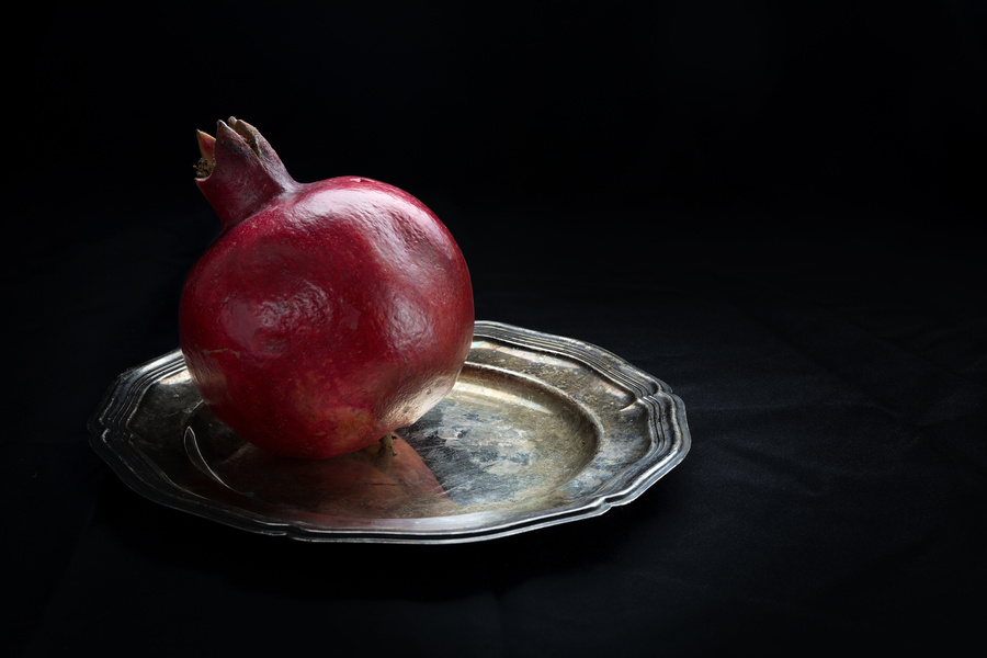 pomegranate on a silver plate,  dark background